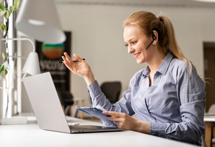 Woman video conferencing on laptop with headset.